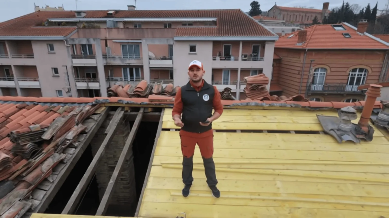Un couvreur sur une toiture en cours de reprise, avec les toits de Toulouse à l’arrière-plan.